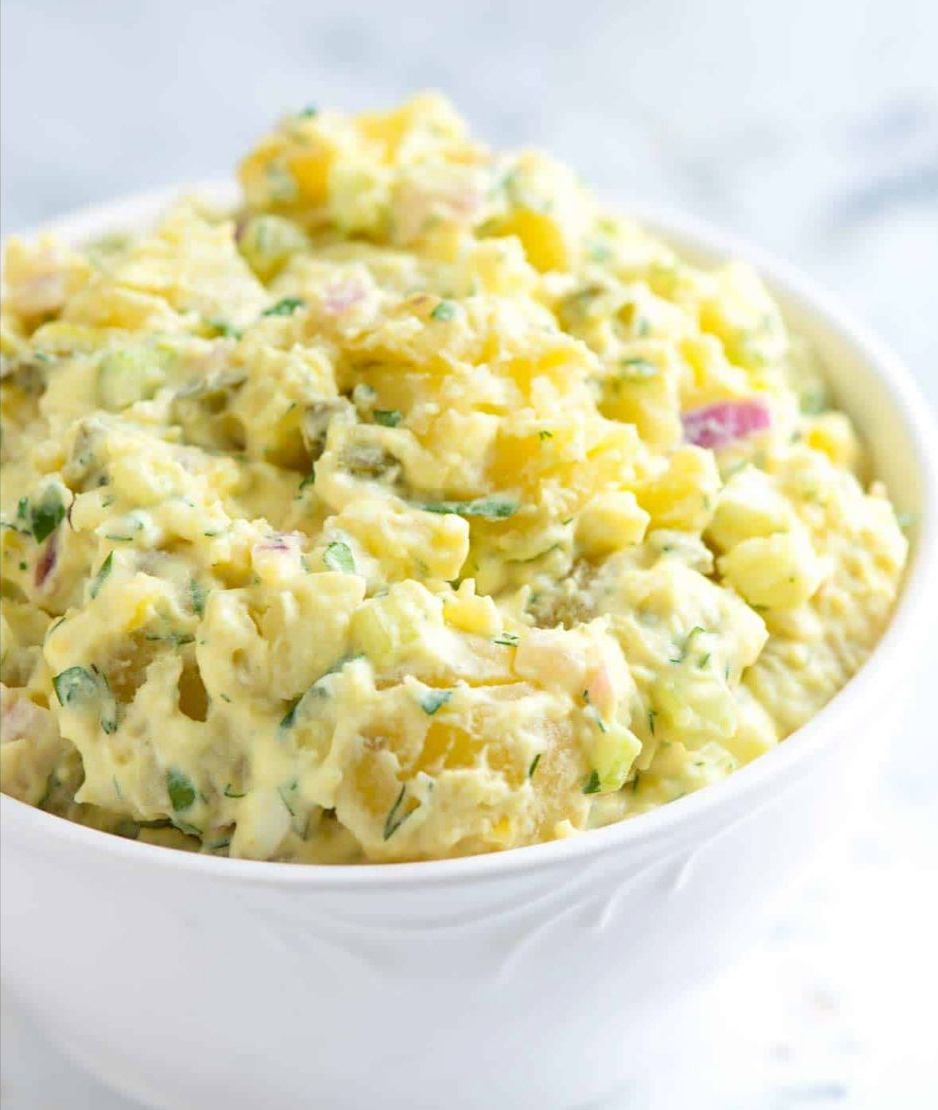 A bowl of potato salad with visible chunks of potato, herbs, and possibly onions.