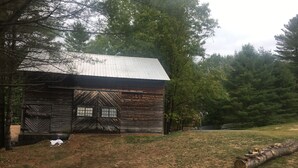 A rustic wooden cabin with a metal roof, large windows, and a door with a chevron pattern. - Blueberry Hill Motel (Long Lake)
