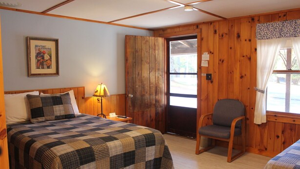 A room with a bed, a chair, a door, and a window. - Blueberry Hill Motel (Long Lake)
