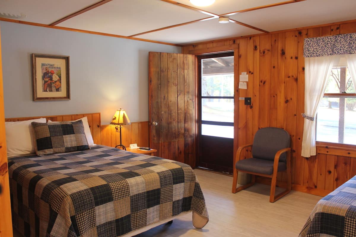Um quarto com uma cama, uma cadeira, uma porta e uma janela.