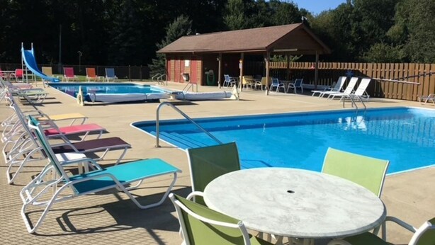 A swimming pool area with lounge chairs and a covered seating area.