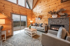 A cozy cabin interior with a stone fireplace, wooden walls, a sofa, and a coffee table. - Blue Ridge Bliss Luxury Cabin with Indoor Pool (Sevierville)