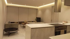 A modern kitchen with a central island, built-in oven, and a dining area with a round table. - Apartamento Náutico 300 (Nuevo Nayarit)