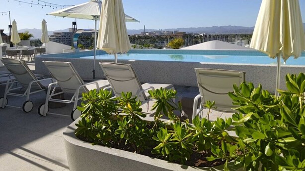 A rooftop pool area with lounge chairs, umbrellas, and string lights. - Apartamento Náutico 300 (Nuevo Nayarit)