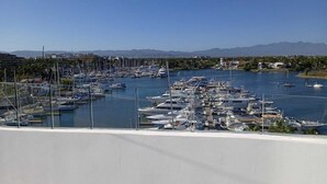 A marina with numerous boats docked, surrounded by a coastal landscape and mountains in the distance. - Apartamento Náutico 300 (Nuevo Nayarit)