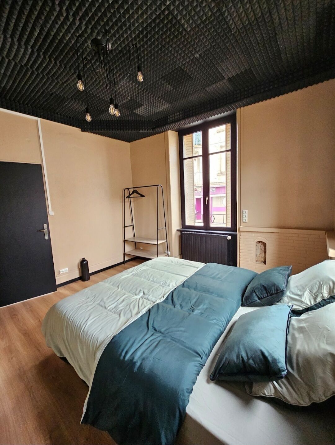 A bedroom with a bed, a radiator, a window, and a door.