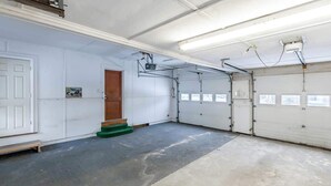 A garage with two doors, a wooden door, and a concrete floor. - White Mountain Escape (Littleton)