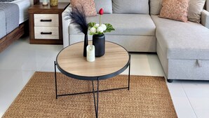 Uma sala de estar moderna com um sofá, uma mesa de centro, uma mesa lateral com uma planta e duas pinturas na parede.