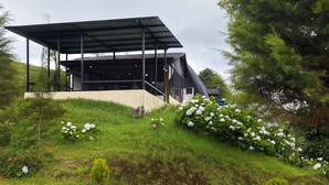 A modern building with a covered outdoor area, surrounded by lush greenery and white flowers. - Cozy cabin surrounded by nature with breathtaking views for total relaxation (Heredia Province)