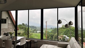 A modern living room with a large window, a dining area, and a sofa. - Cozy cabin surrounded by nature with breathtaking views for total relaxation (Heredia Province)