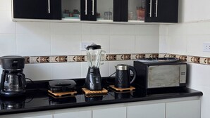 Una cocina moderna con gabinetes negros, una encimera negra y una lámpara colgante.