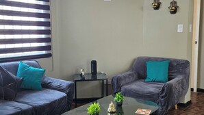 Una sala de estar con dos sofás, una mesa de centro y una lámpara colgante.