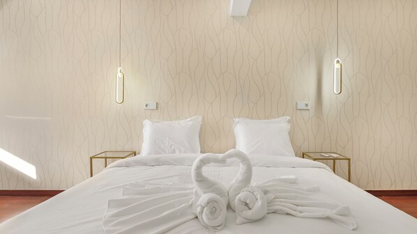 A hotel room with a large bed, two bedside tables, and a wall-mounted light fixture.