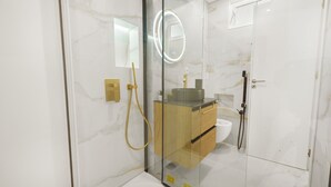 Een moderne badkamer met een douchecabine van glas, een wastafelmeubel en een toilet.