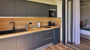 Una cocina moderna con armarios oscuros, encimera de madera y un refrigerador pequeño.
