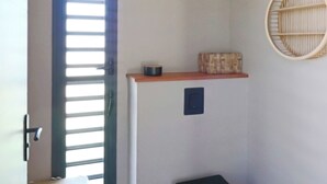 Una habitación con puerta corredera, una pequeña mesa con un recipiente, estante fijado a la pared y un estante circular tejido.