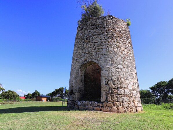A stone tower with a large arched entrance, surrounded by a grassy field and trees. - Villa Gligli with swimming pool and view of the mill, ideal for 4 people (Saint-Louis)