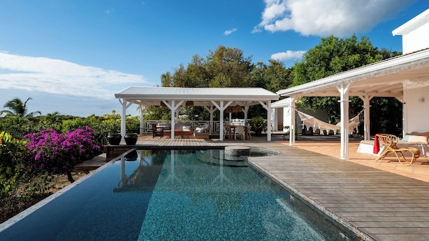 A poolside area with a covered seating area, a hammock, and a wooden deck. - Villa Blanche with magnificent sea views and infinity pool at your disposal (Grand-Bourg)