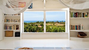 A bedroom with a large window offering a view of a lush landscape and the sea. - Villa Blanche with magnificent sea views and infinity pool at your disposal (Grand-Bourg)