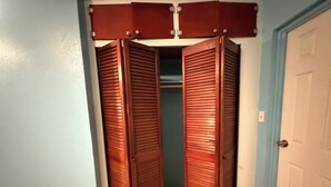 Een kast met schuifdeuren, een deur aan de rechterkant en een lichtschakelaar op de muur.