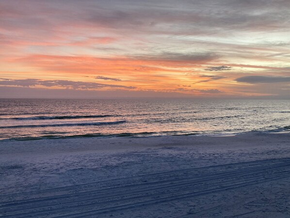 Ein Strand mit Wellen und einem Sonnenuntergang.