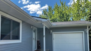 A residential house with a garage, a front door, and a small porch. - Charming 3-bedroom Lake Cottage with Dock, WiFi, & AC on enjoyable Houghton Lake (Houghton Lake)