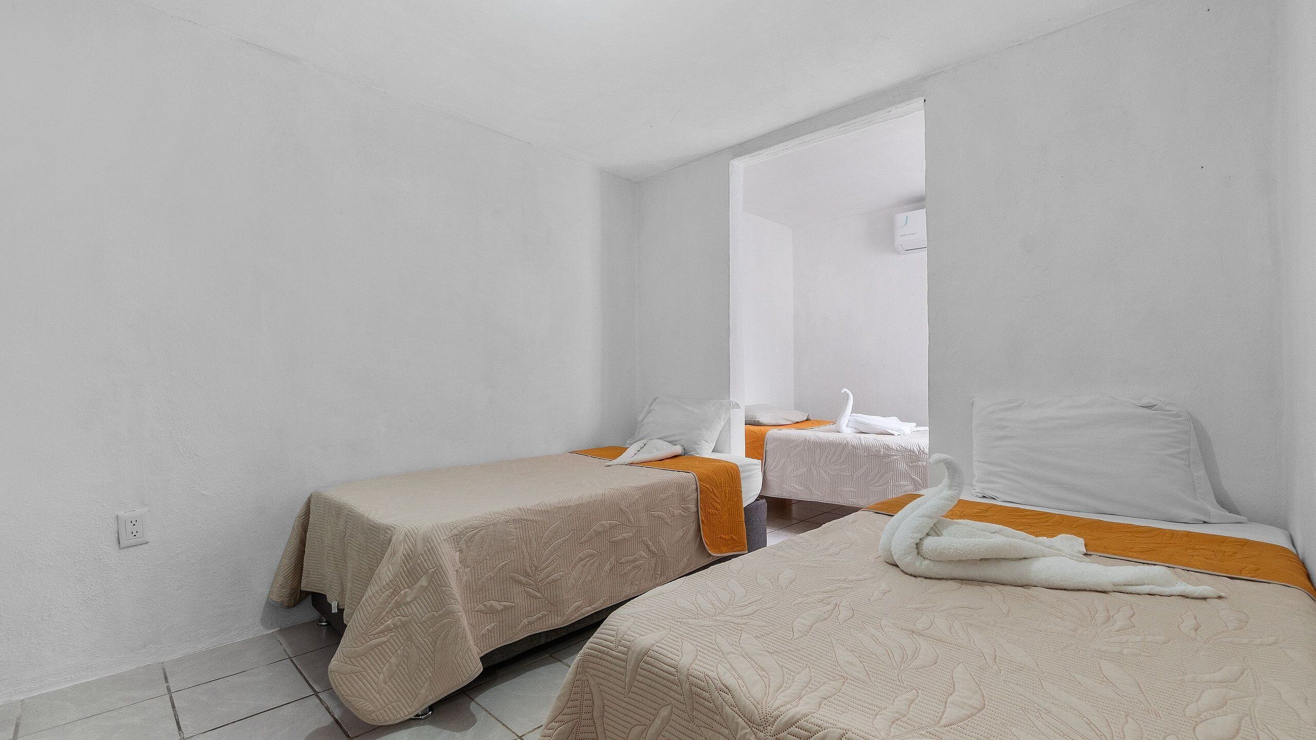 A small, clean room with two beds, a mirror, and a window.