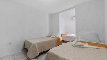 A small, clean room with two beds, a mirror, and a window.
