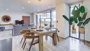 A modern living room with a wooden dining table, grey sofa, and large windows. - Porto 15 Condominios (Puerto Vallarta)