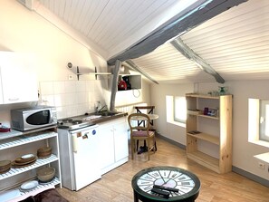 A compact kitchen with a microwave, stove, and wooden shelves. - Fully furnished and equipped studio apartment, right in the town center (limoges)