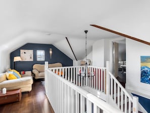 A loft-style living area with a high ceiling, a white railing, and a staircase leading to an upper level. - Suantraí Cottage (Cashel)