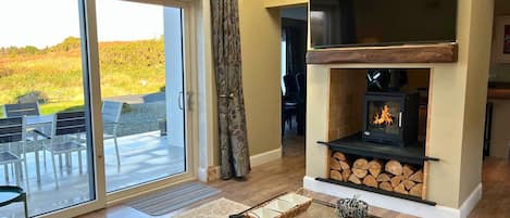 Cozy living room with a fireplace, comfortable seating area, and a view of the outdoors through a sliding glass door.