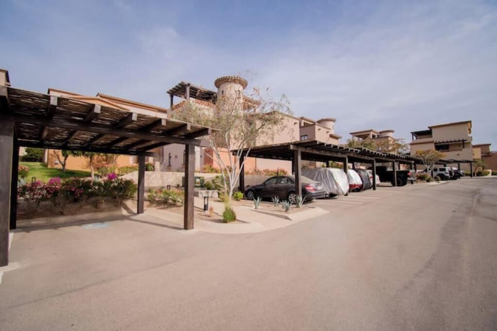 A parking area with covered carports and a building with a cylindrical tower in the background.