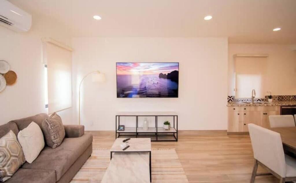 Een moderne woonkamer met een bank, salontafel en een aan de muur bevestigde televisie.