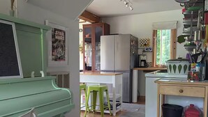 Una cocina compacta con un piano, un refrigerador y una pequeña zona de comedor con taburetes.