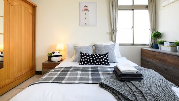 Un dormitorio con cama, mesita de noche, armario, ventana con cortinas e imagen colgada en la pared.