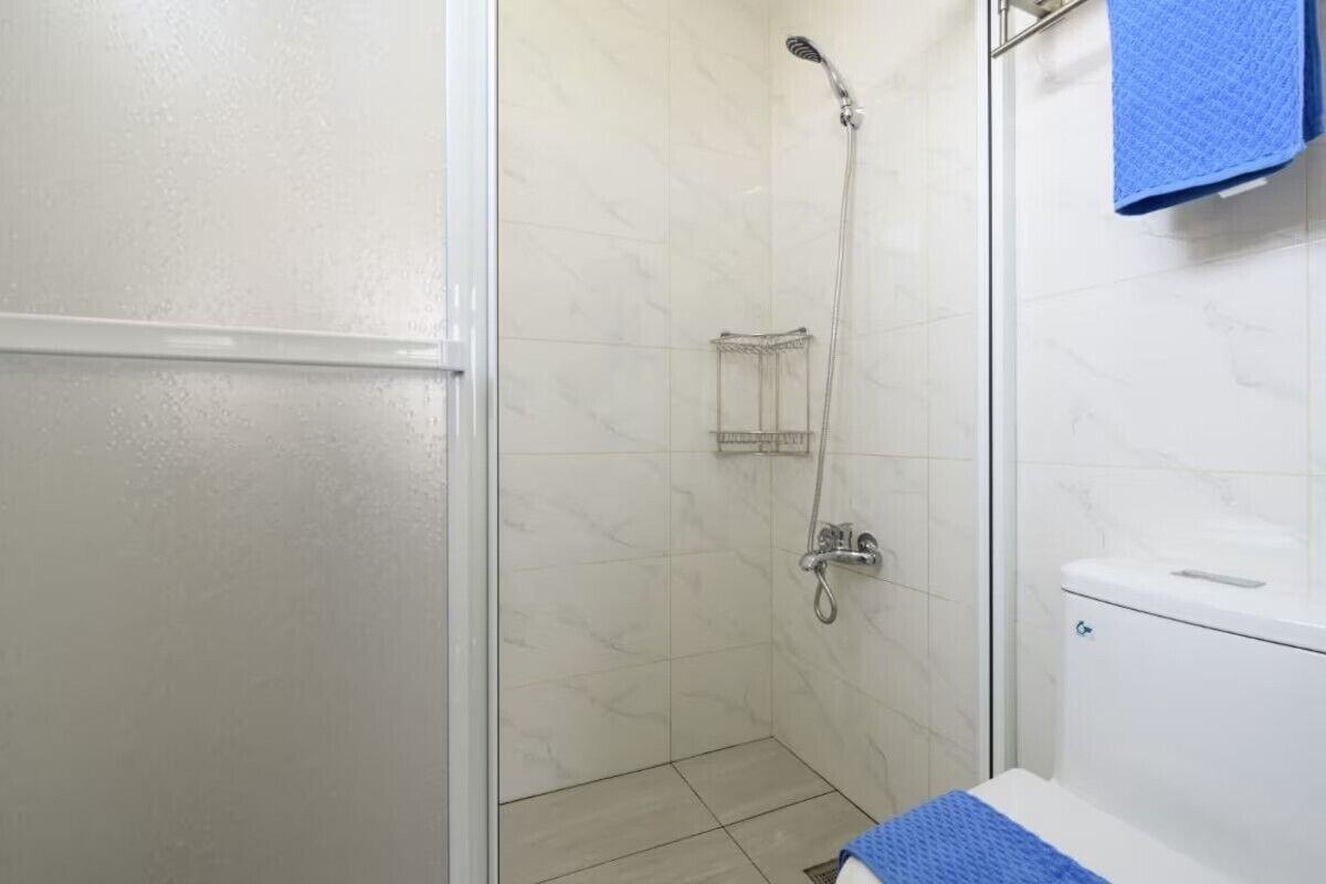 Un baño con ducha, inodoro y toallero.