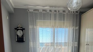 Un dormitorio con cama, un reloj, una ventana con cortinas y un armario.