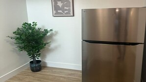 Une cuisine moderne avec un réfrigérateur en acier inoxydable, une plante en pot et une œuvre d’art encadrée accrochée au mur.