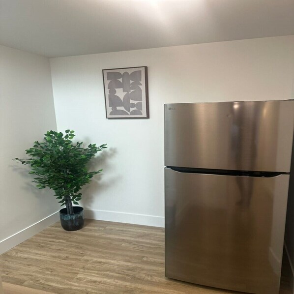 Eine moderne Küche mit einem Edelstahl-Kühlschrank, einem Blumentopf und einem gerahmten Kunstwerk an der Wand.