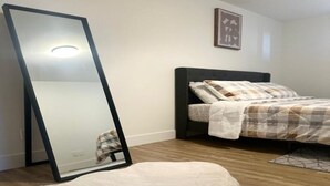Une chambre à coucher avec un lit, un grand miroir et un tapis blanc à poils longs.