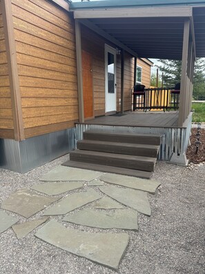 A wooden exterior with a covered porch and stone steps leading to a door. - Charming house with fenced yard in Driggs for a cozy getaway (Driggs)