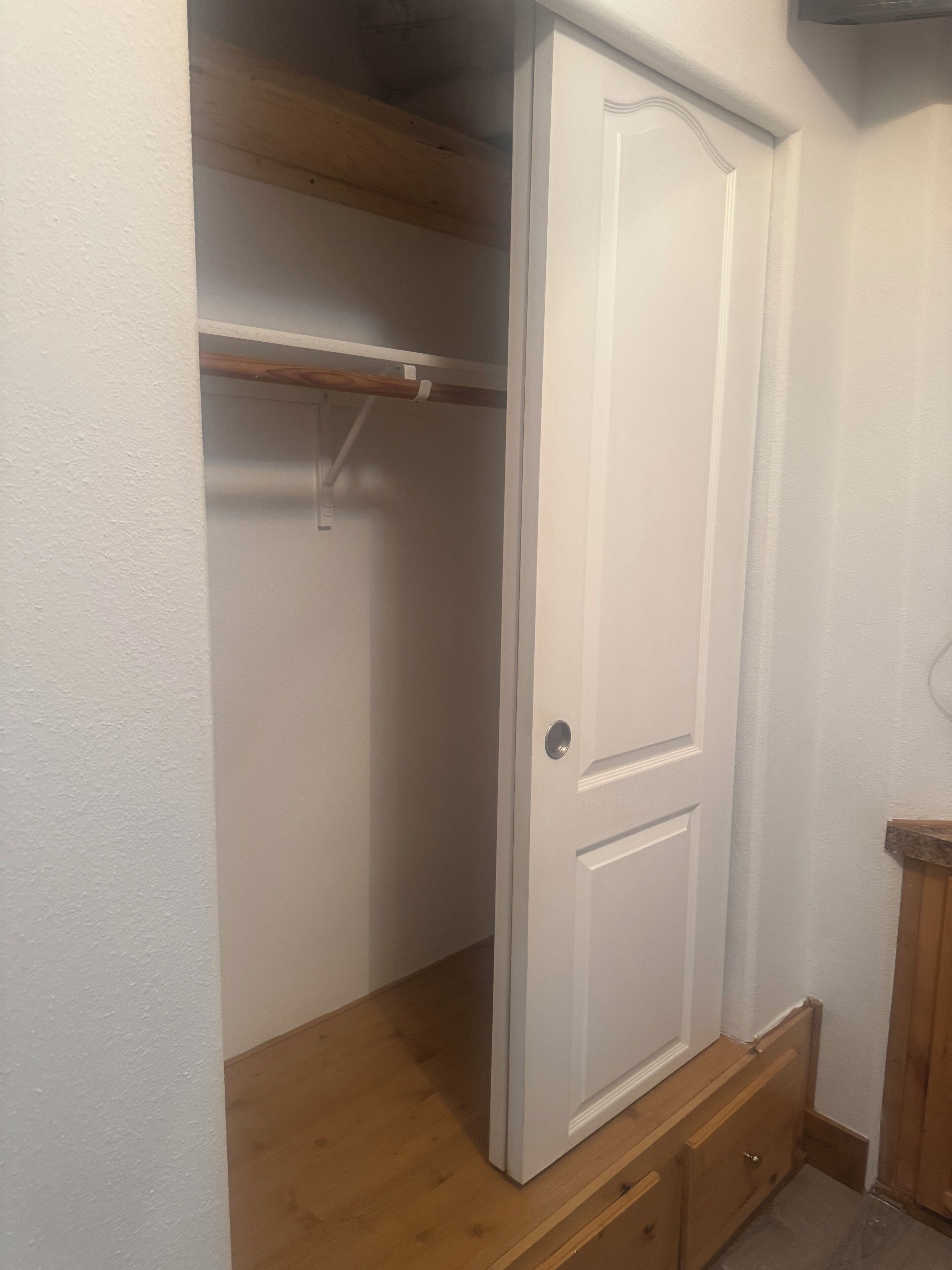 Een kast met een houten plank en een witte deur.
