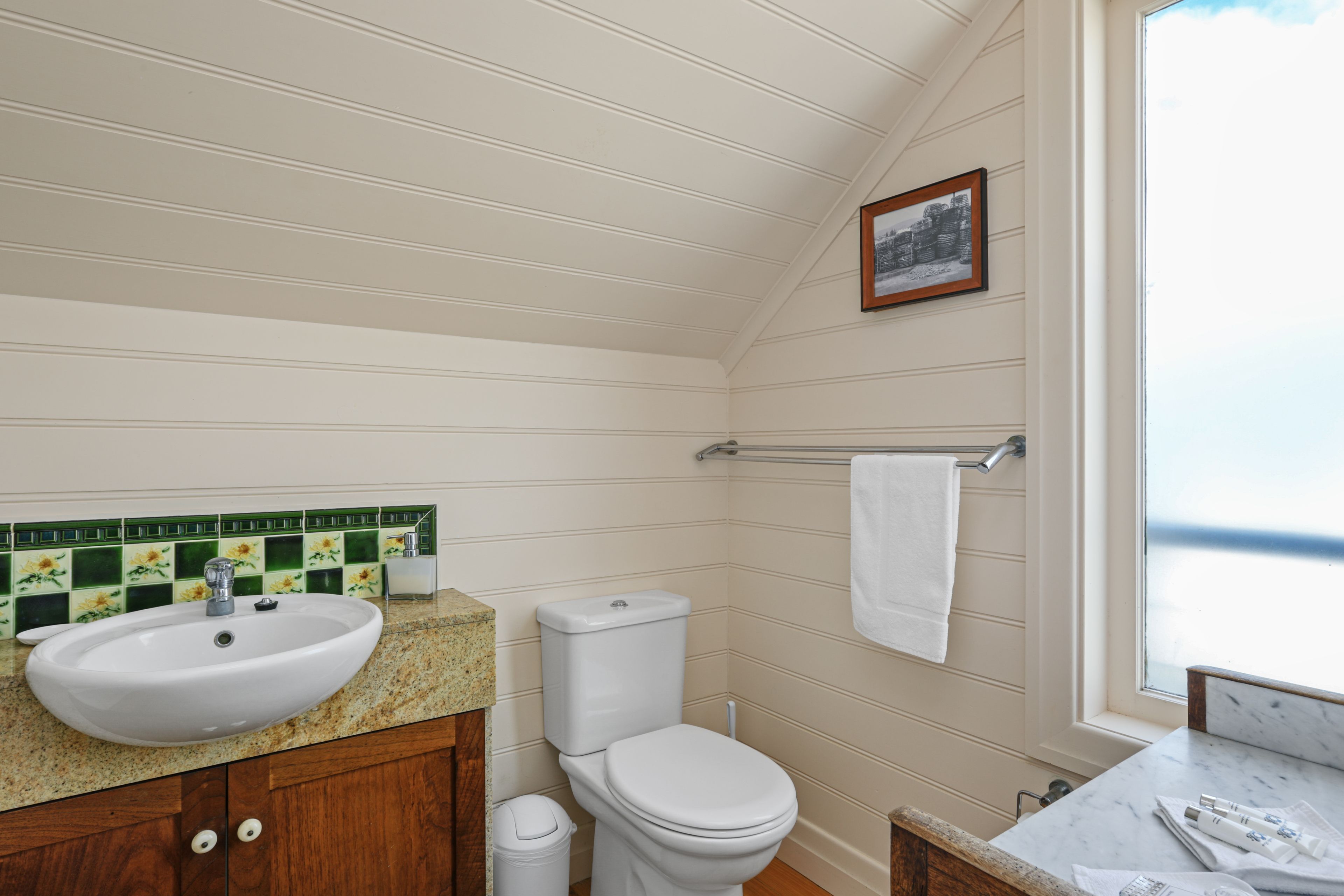 A bathroom with a white sink, toilet, and a towel rack.