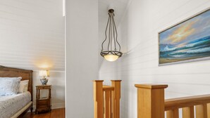 A bedroom with a wooden bed, a bedside table with a lamp, and a painting of a seascape on the wall. - Apollo Bay Guesthouse (Apollo Bay)