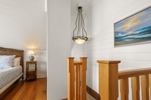 Een slaapkamer met een houten bed, een nachtkastje met een lamp, en een schilderij van een zeegezicht aan de muur.