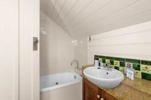 A bathroom with a bathtub, a sink, and a vanity with a mirror.