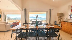 A dining area with a table set for four, a view of the sea, and a balcony with a sofa. - Villa Golfo Di Sogno (porto vecchio)