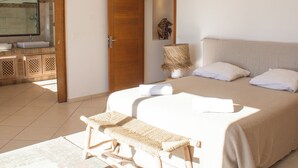 A bedroom with a large bed, a bedside lamp, and a bathroom with a sink and mirror. - Villa Golfo Di Sogno (porto vecchio)