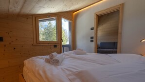 Ein Holzhütten-Zimmer mit einem Bett, einem Fenster und einer Tür.